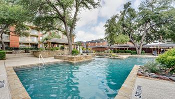 A swimming pool surrounded by trees and a stone wall.